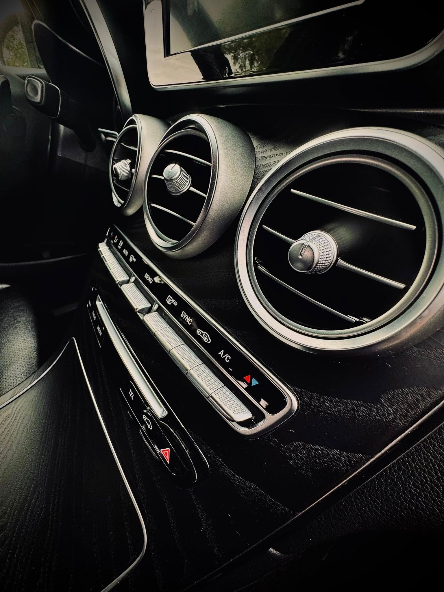 Interior car dashboard featuring silver air vents and climate control panel.