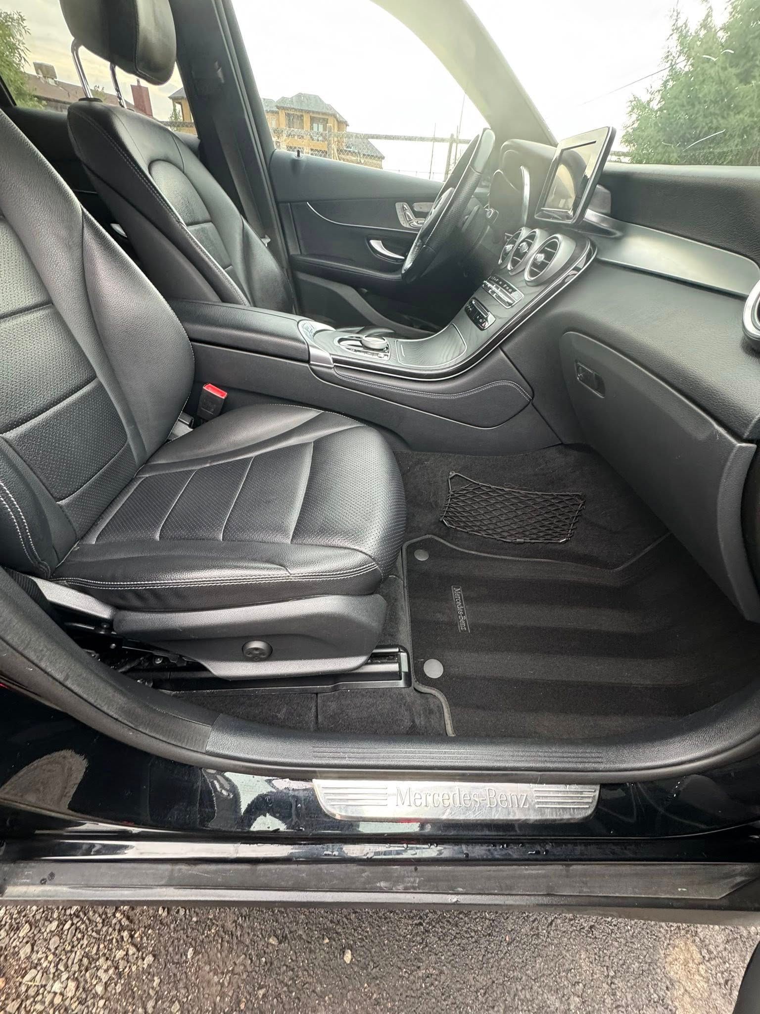 Black Mercedes-Benz car interior with leather seats, dashboard, and floor mats.