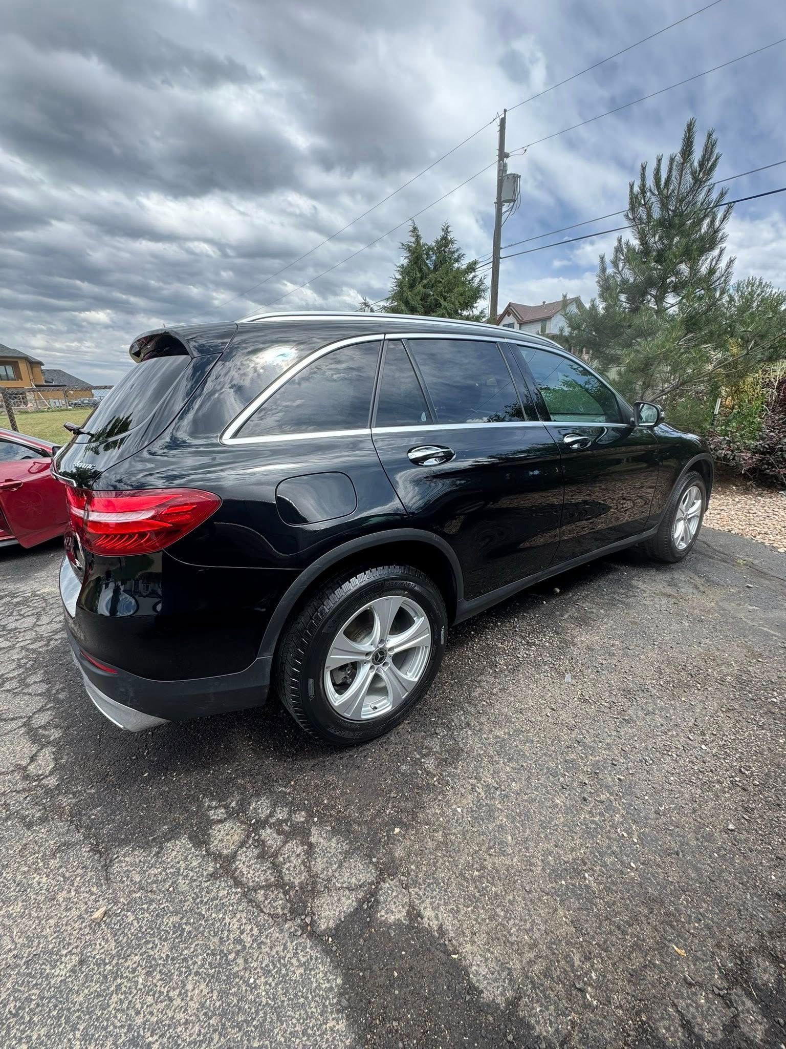 Black SUV parked outdoors on a gravel driveway, under a cloudy sky.