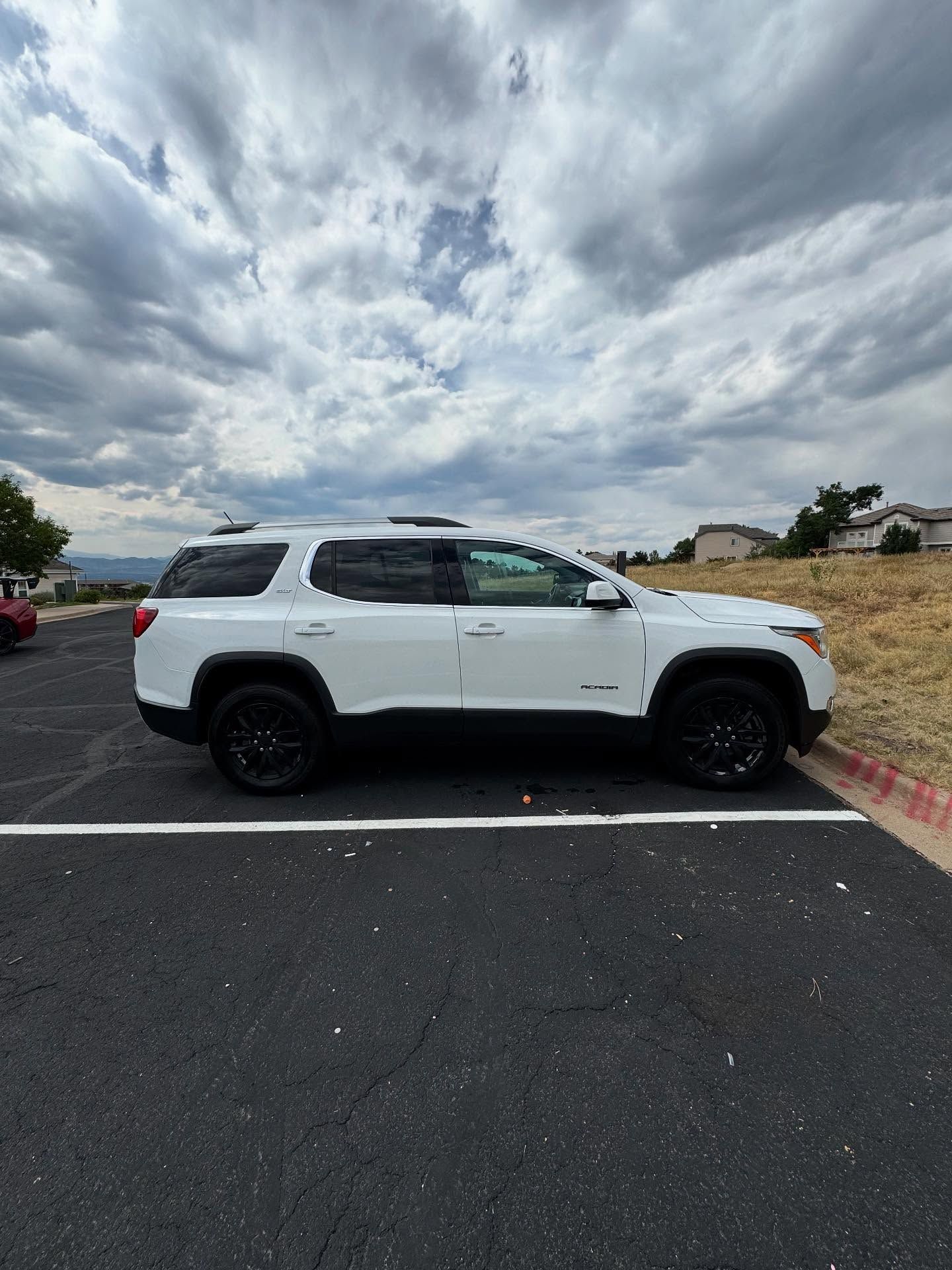 White SUV parked on asphalt under a cloudy sky.