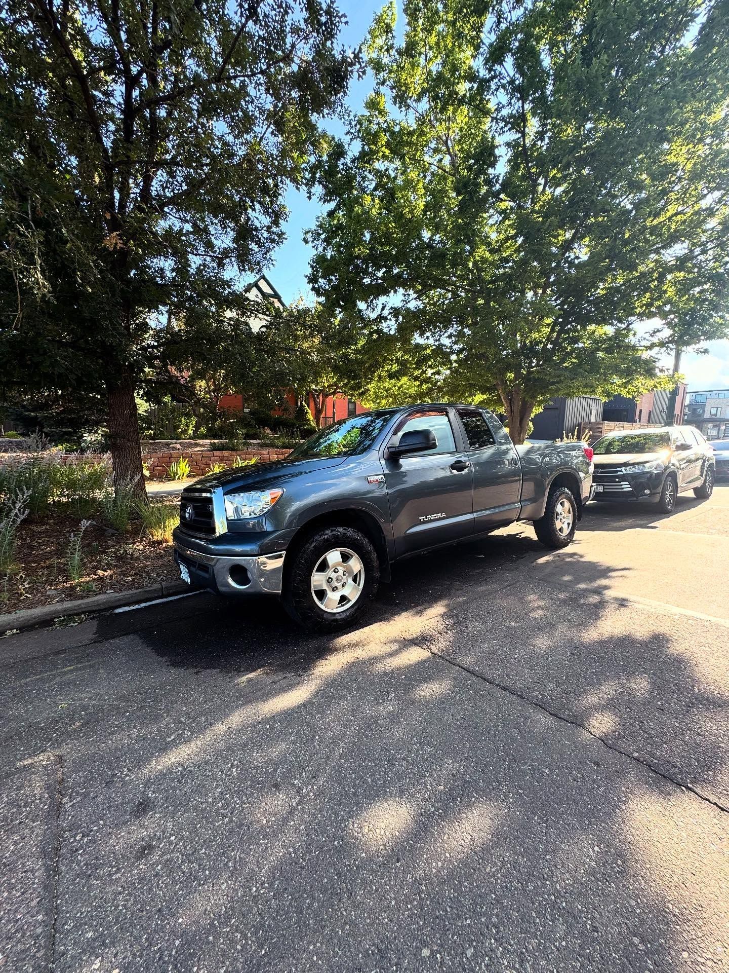 Gray Toyota Tundra parked on a street, trees in the background.