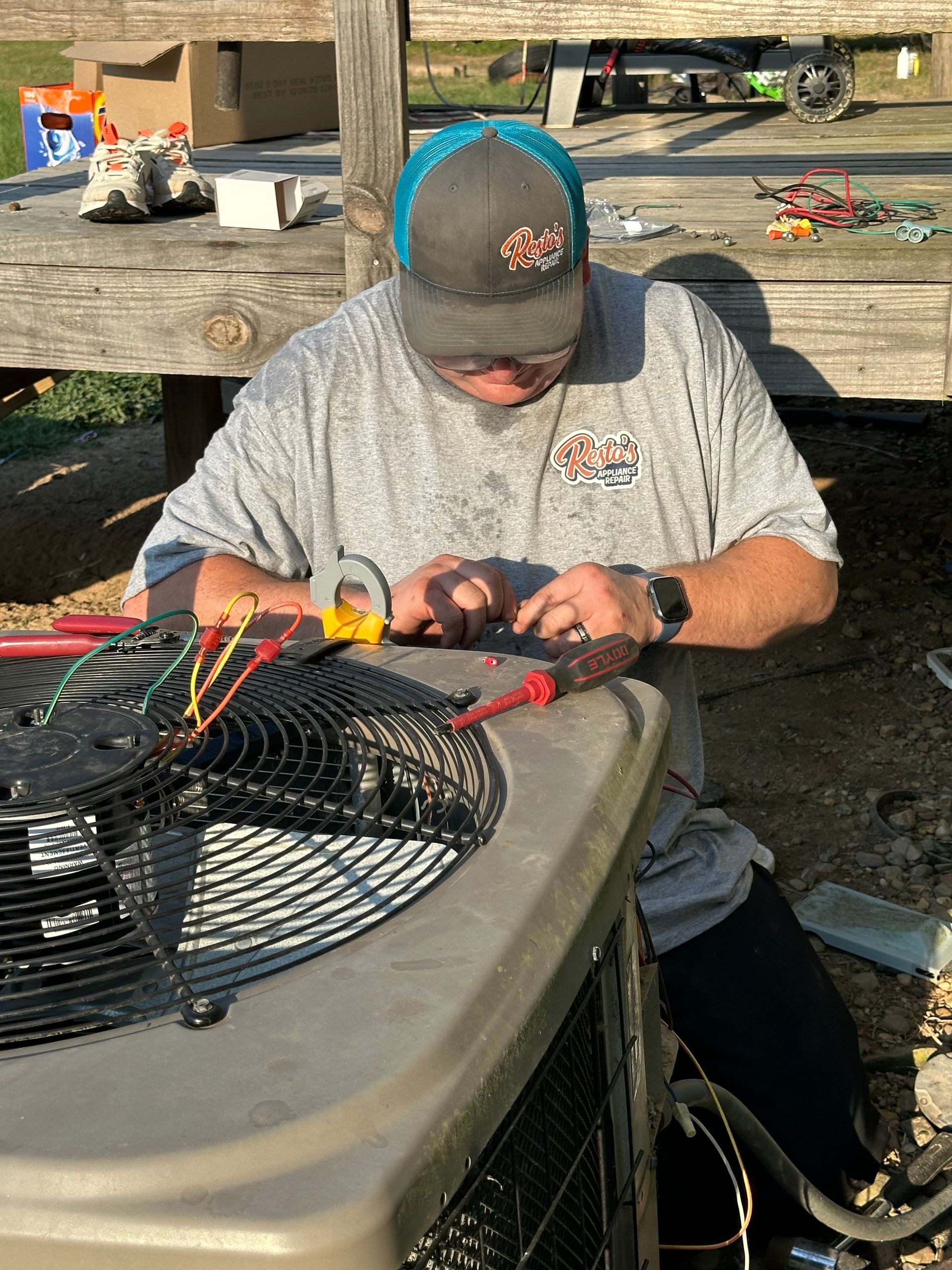 Person working on wiring beside an outdoor air conditioner unit