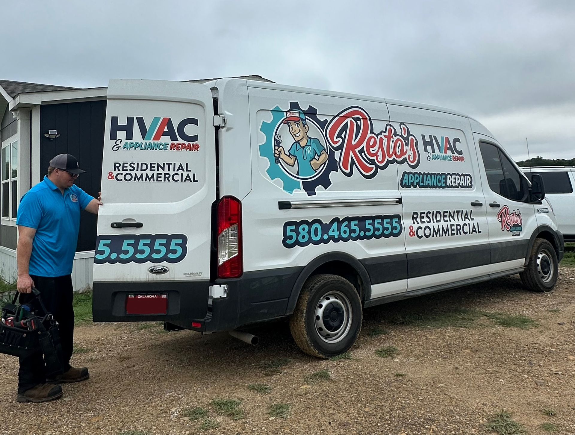 White HVAC service van parked outdoors with company logos and phone number on the side