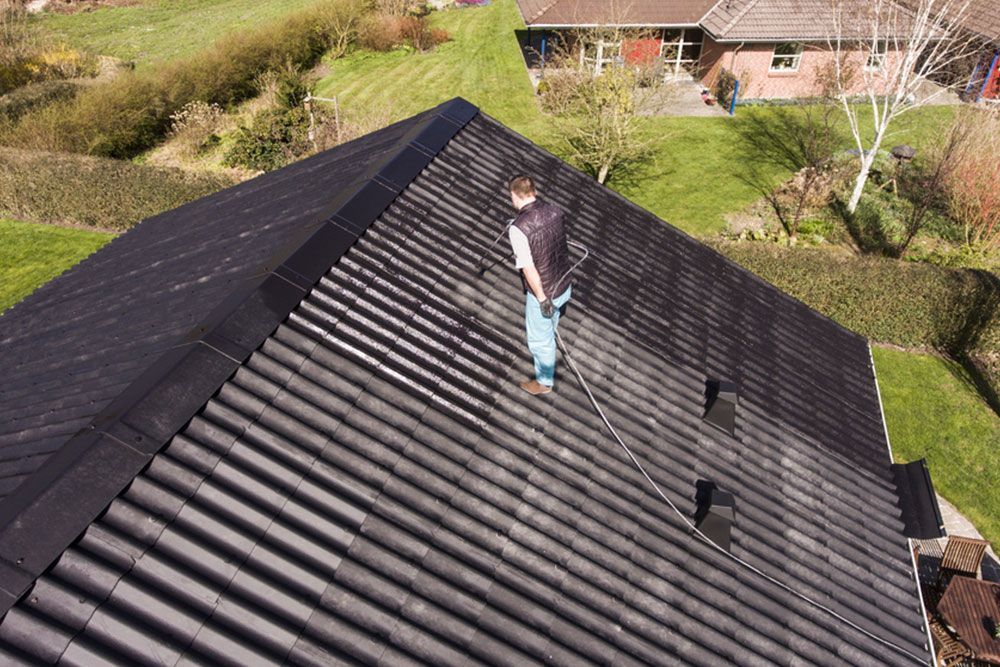 Man painting the roof black — Roof Painting in Fraser Coast, QLD