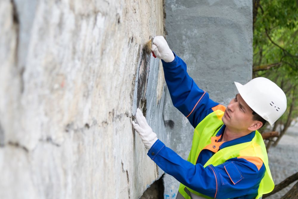 Man removing the graffiti on a wall using a wire brush — Interior Painting in Maryborough, QLD