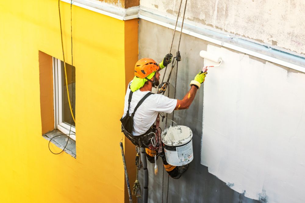 Man using paint roller to paint the exterior walls of a house — Interior Painting in Hervey Bay, QLD