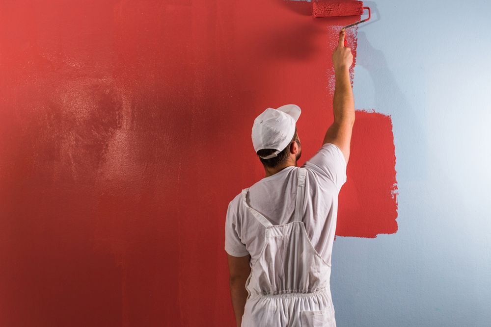 Man using paint roller to colour the walls red — Epoxy Flooring in Fraser Coast, QLD