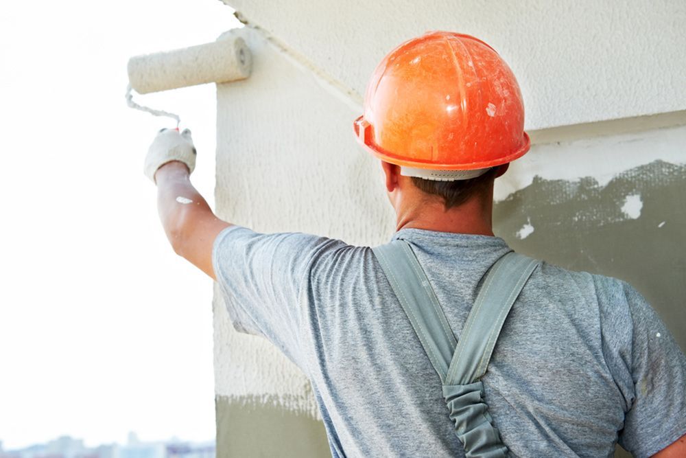 Man wearing orange safety helmet while painting the exterior walls of the house — Exterior Painting Near Me in Fraser Coast, QLD