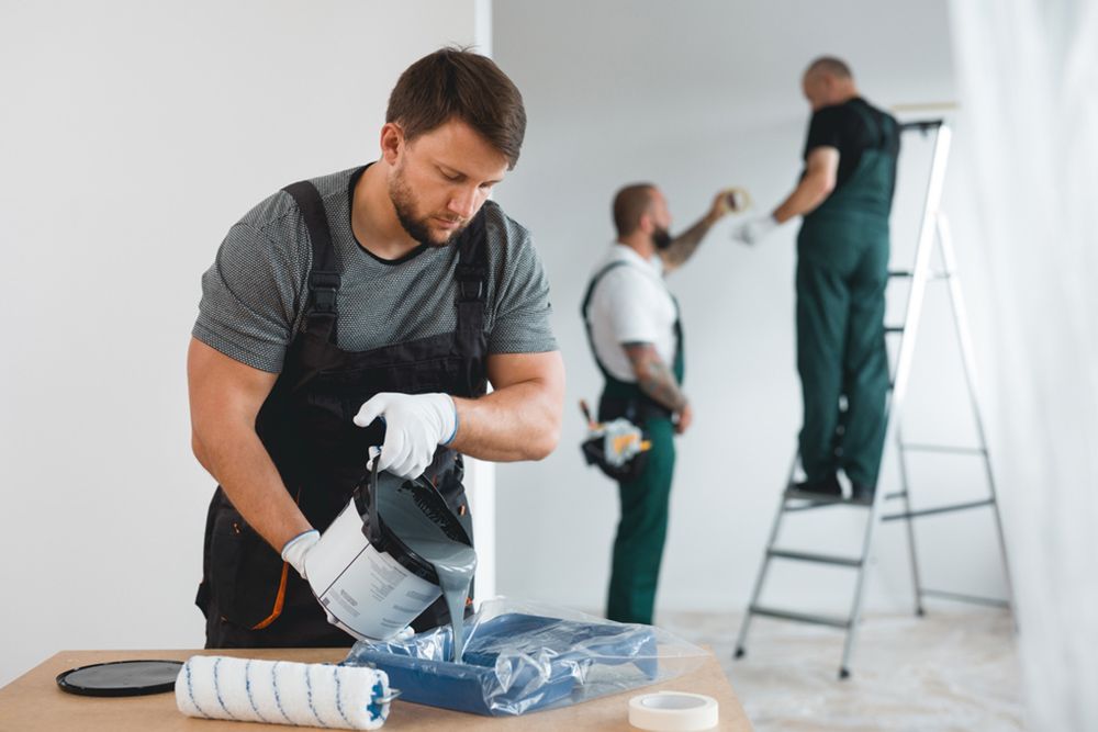 Painter pouring the grey paint in the container — Contact us in Fraser Coast, QLD