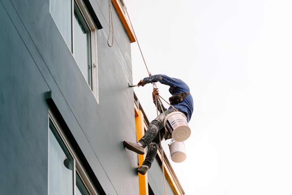 Painter suspended by a harness to paint the outside walls of the house — Commercial Painter in Fraser Coast, QLD
