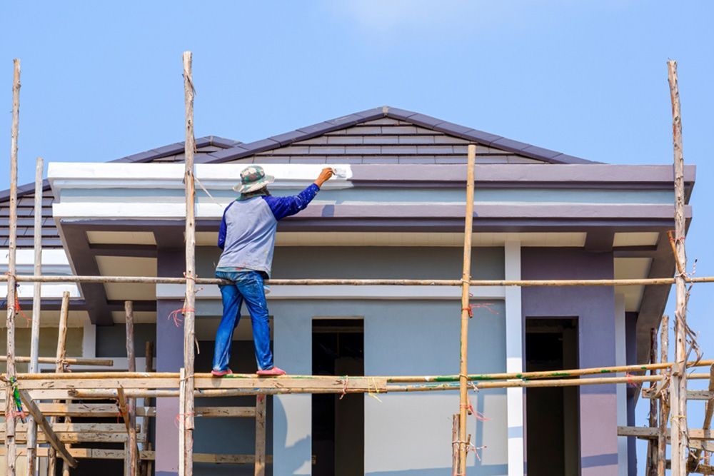 Painter using scaffolding to paint the upper part of the house — Interior Painting in Maryborough, QLD