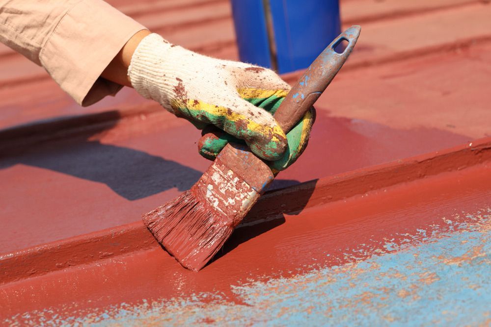 Worker painting the roof red using a brush — Roof Painting in Fraser Coast, QLD