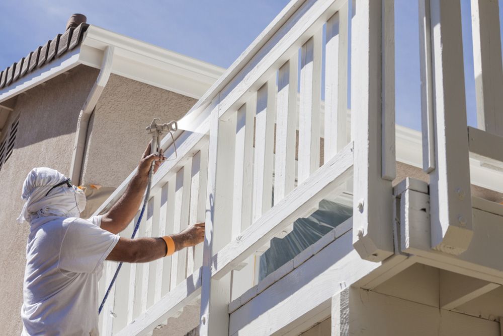 Professional painter using spray gun to paint the balcony balustrades — House Painting in Fraser Coast, QLD