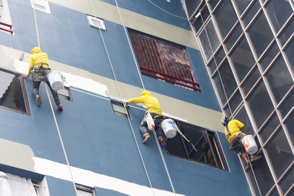 Three painters suspended on harnesses to paint the outside walls of a building — Interior Painting in Hervey Bay, QLD