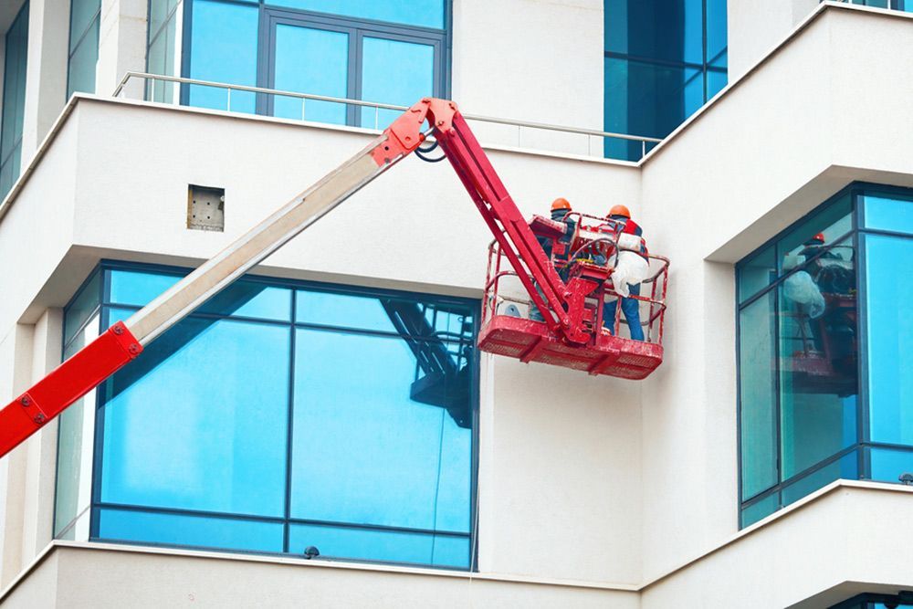 Painters in a boom lift painting the walls of a building — Commercial Painter in Fraser Coast, QLD