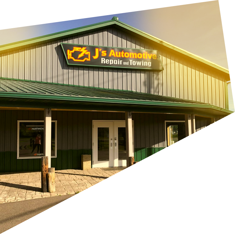 Exterior of J's Automotive Repair and Towing with a gray and green metal building, large white doors, and a stone patio. | J's Automotive
