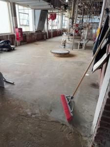 Long, concrete floor with a red squeegee; industrial setting.