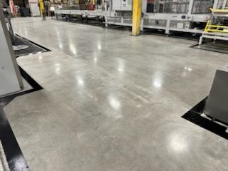 Polished concrete factory floor with machinery, bright lighting, and black borders.
