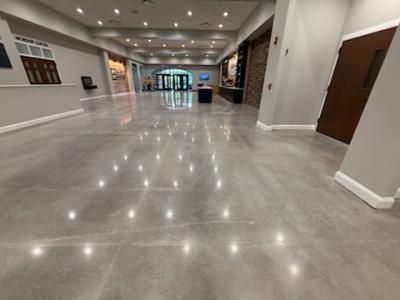 Polished concrete floor reflecting lights in a spacious building lobby.