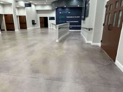 Empty modern lobby with polished concrete floor, doors, and a wall with inspirational text.
