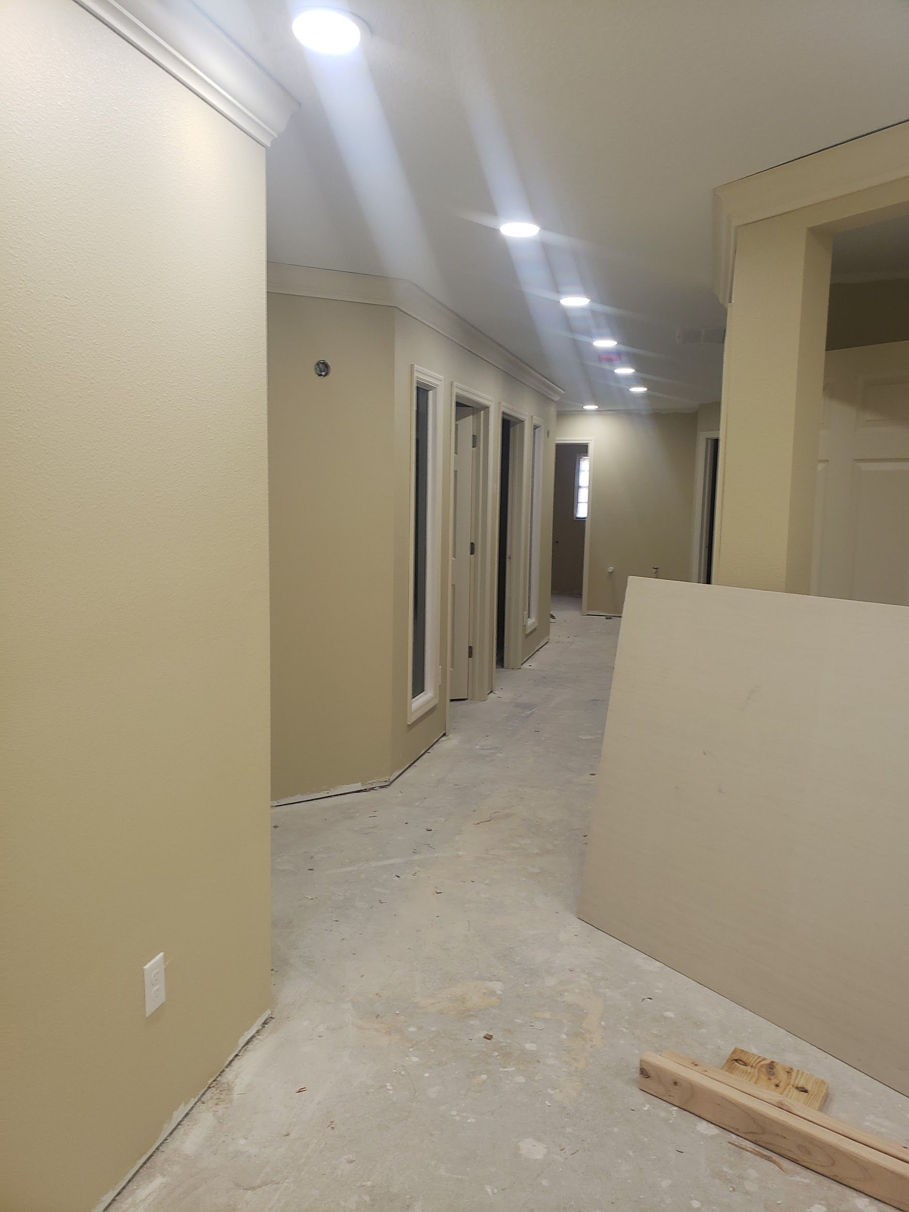 A long hallway with a lot of windows and doors in a house under construction.