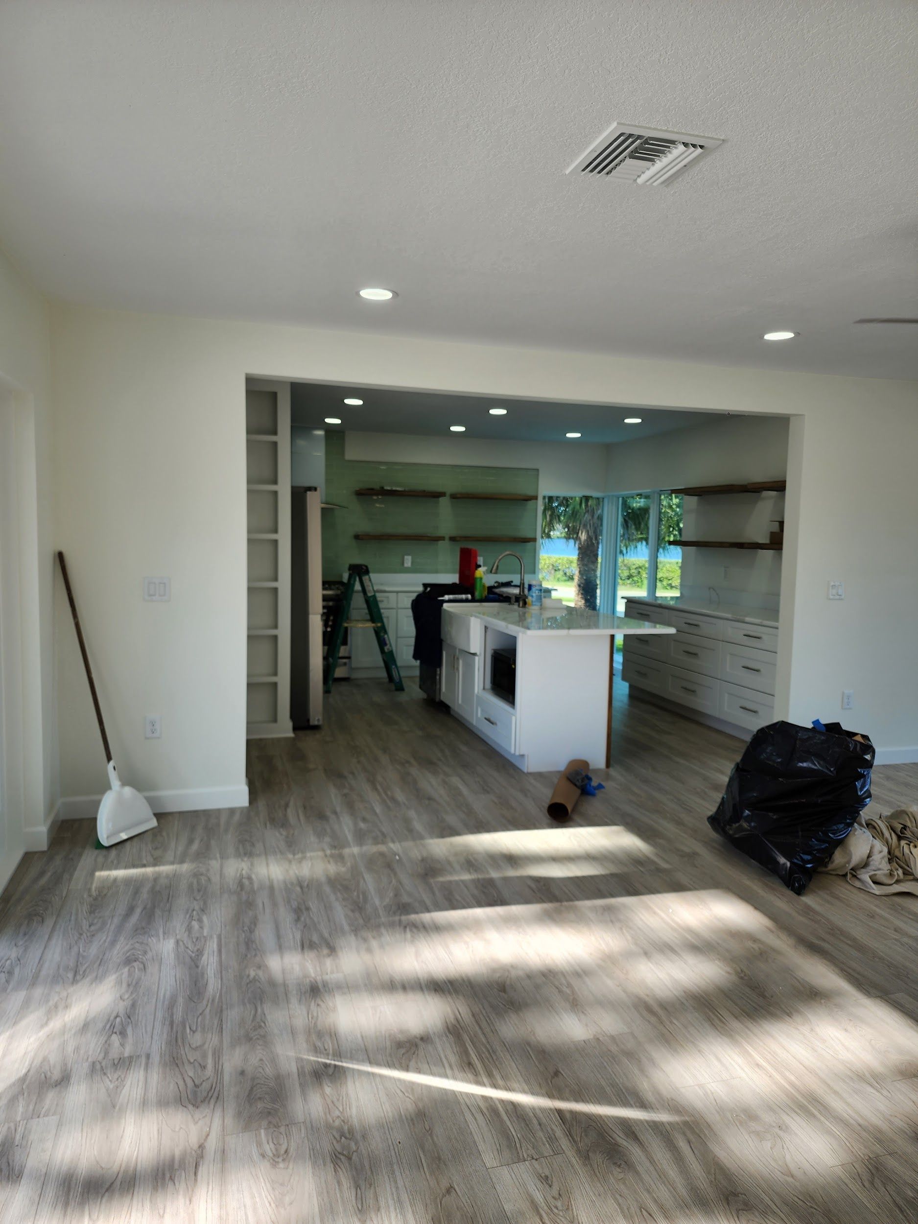 A living room with hardwood floors and a kitchen in the background.