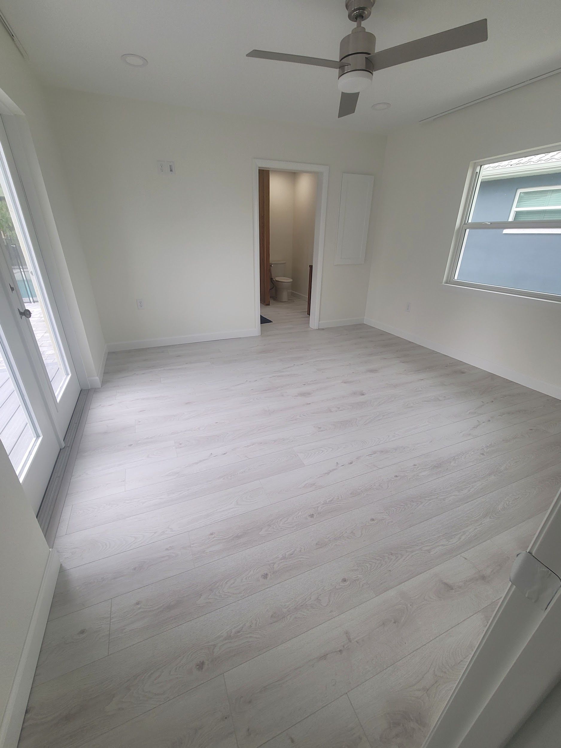 An empty room with a ceiling fan and a window.