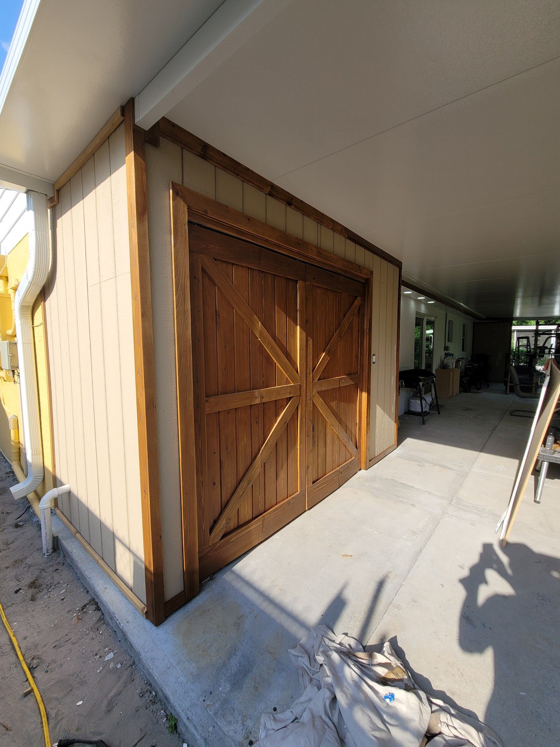 A wooden garage door is being installed on the side of a house.