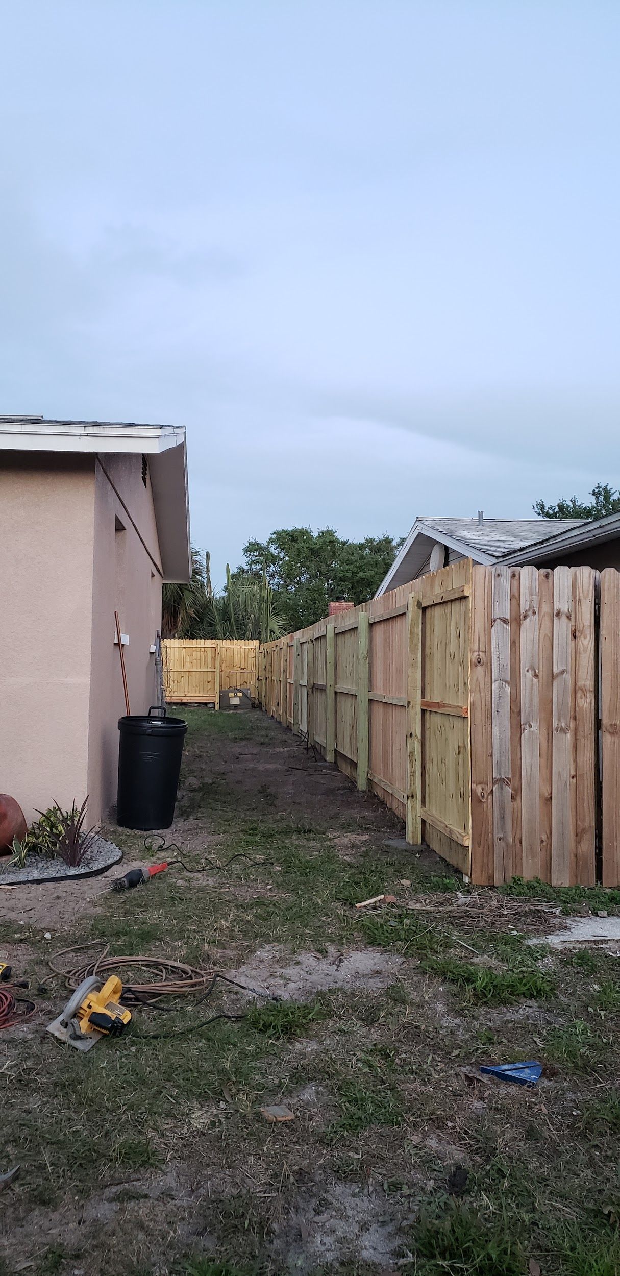 A wooden fence is being built in the backyard of a house.
