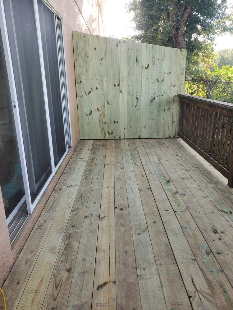 A wooden deck with a fence and sliding glass doors.