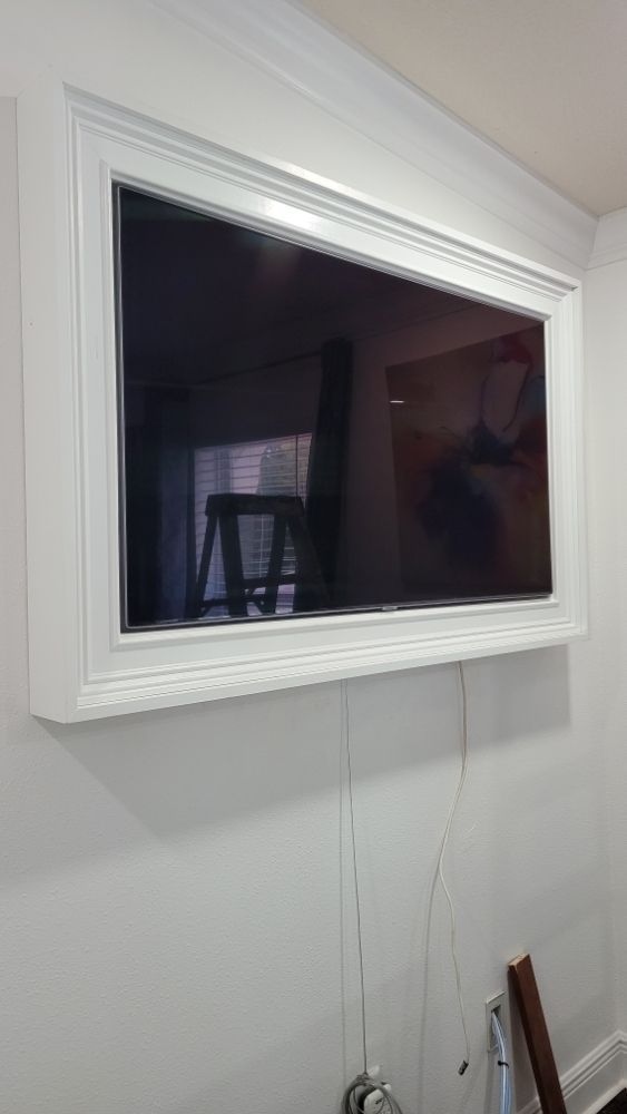 A flat screen tv is mounted on a white wall in a living room.