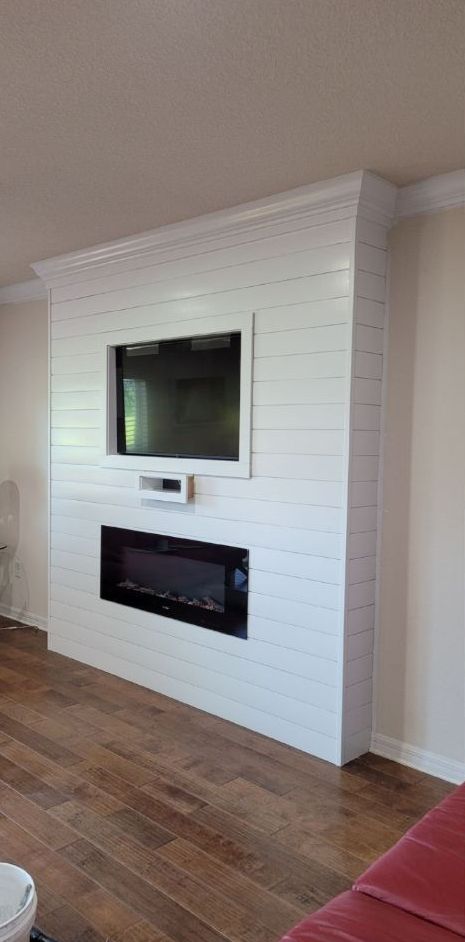 A living room with a fireplace and a flat screen tv on the wall.