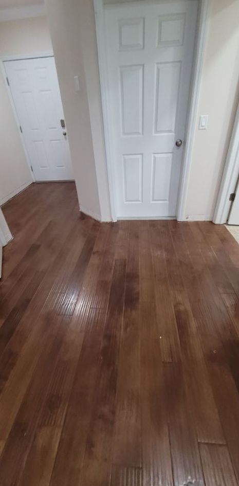 A hallway with hardwood floors and a white door.