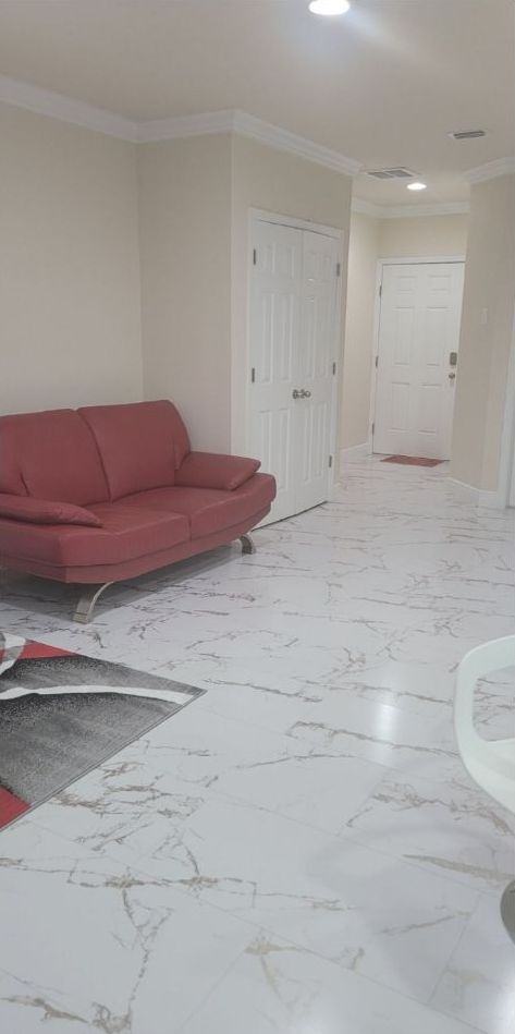 A living room with a red couch and white tile floor.