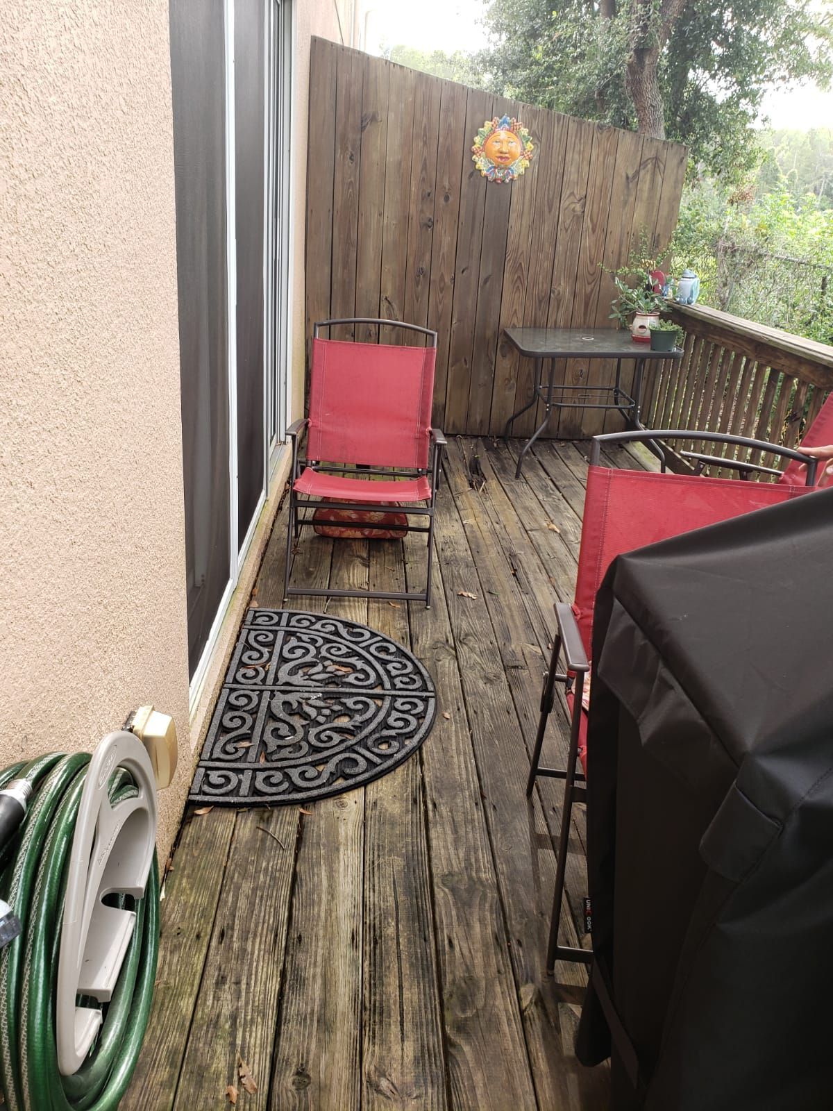 A wooden deck with chairs , a table and a grill.