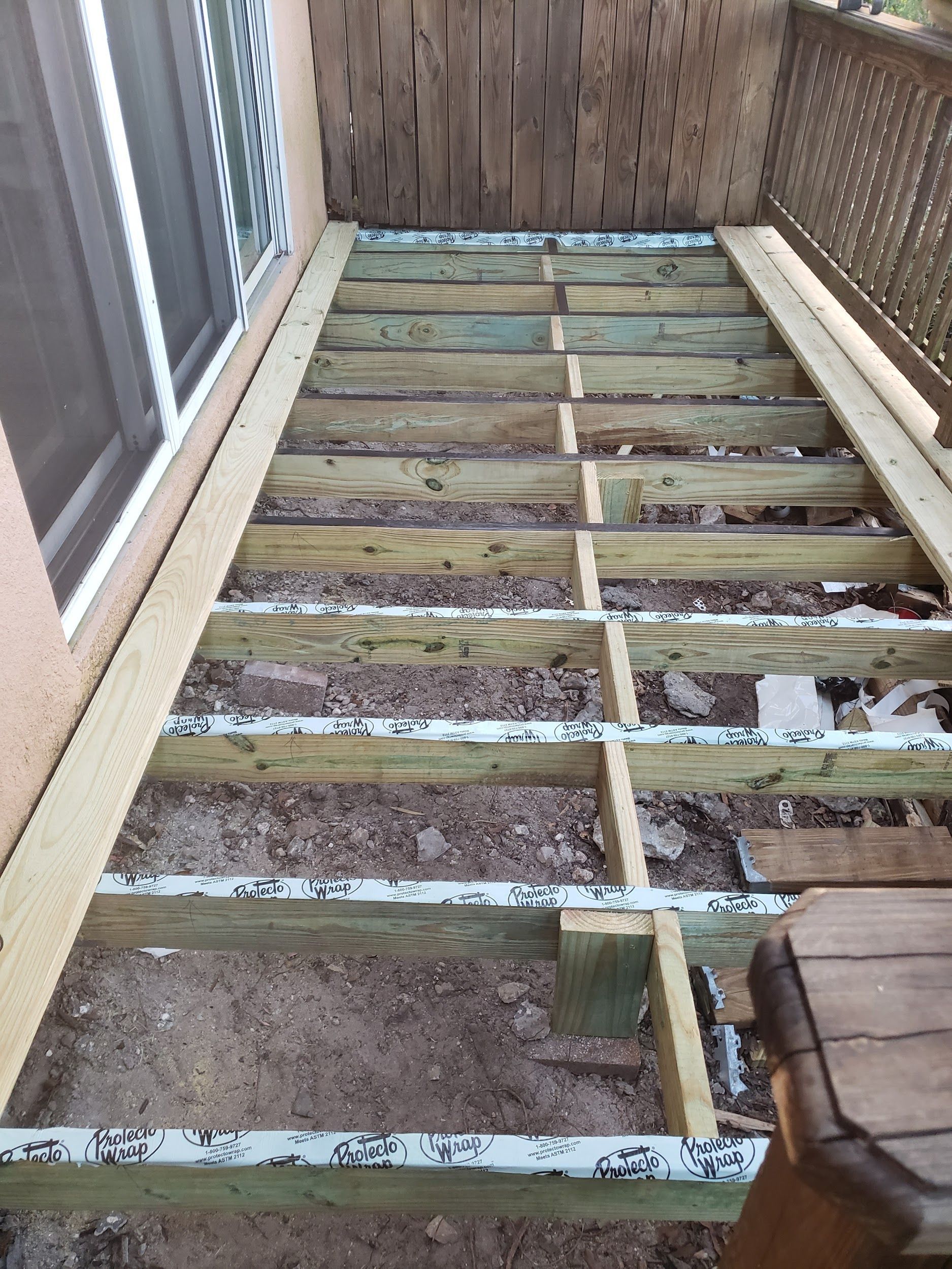 A wooden deck is being built on the side of a house.