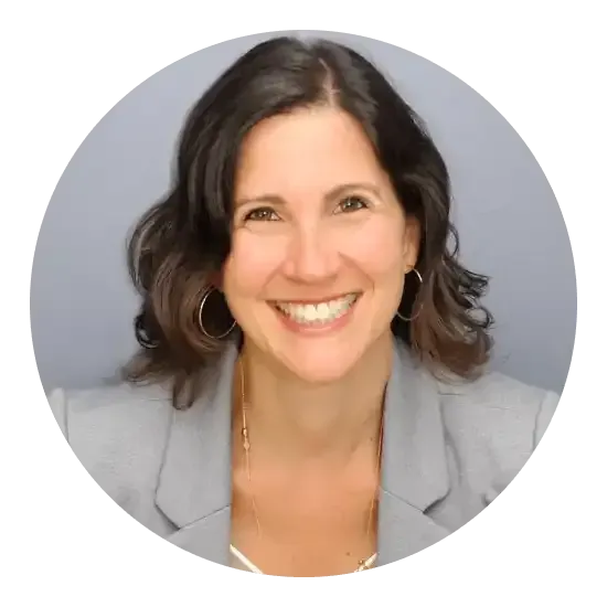 Femme aux cheveux foncés, souriante, portant un blazer gris.