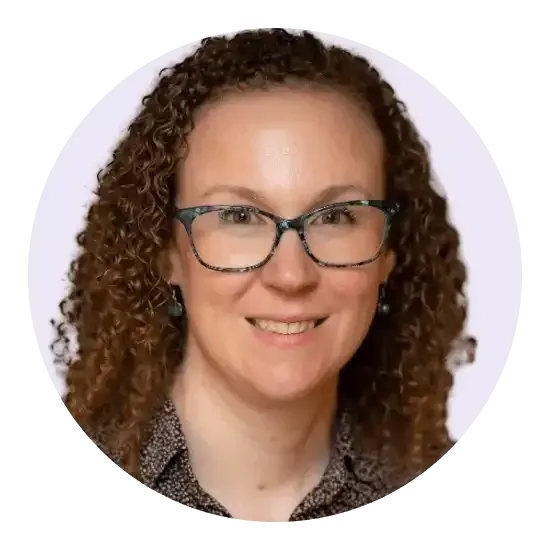 Femme aux cheveux bouclés et portant des lunettes, souriante.