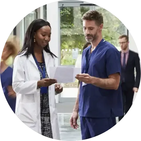 Deux soignants consultent un document dans un couloir d'hôpital.