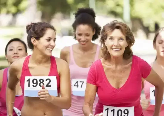 Des femmes en hauts roses participent à une course en extérieur ; l'une d'elles sourit, portant le dossard numéro 1109.