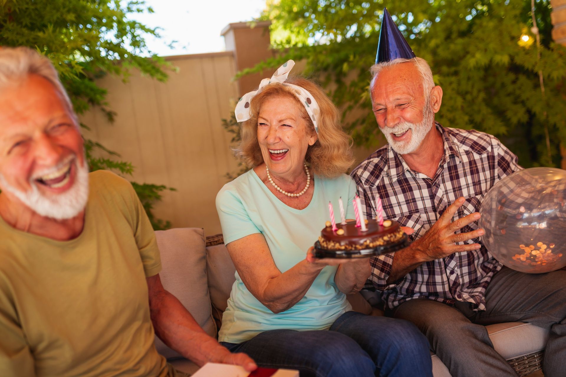A group of elderly people are sitting on a couch celebrating a birthday.