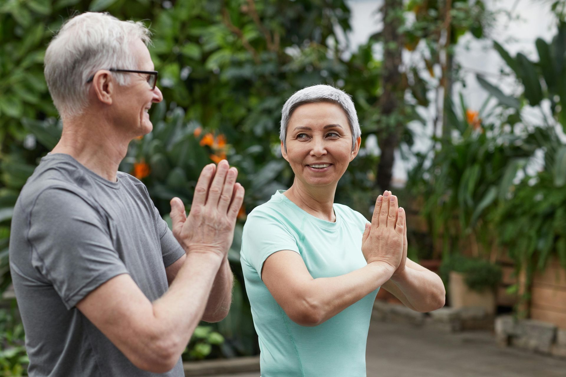 A man and a woman are doing yoga together in a park.