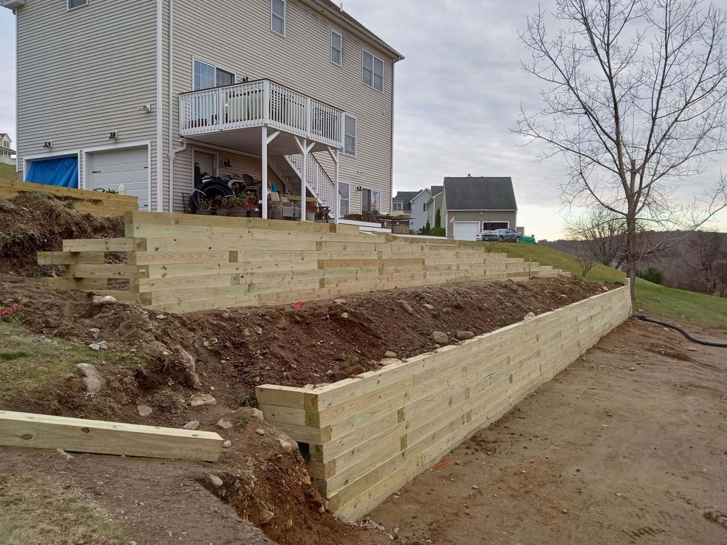 A wooden retaining wall is being built in front of a house.