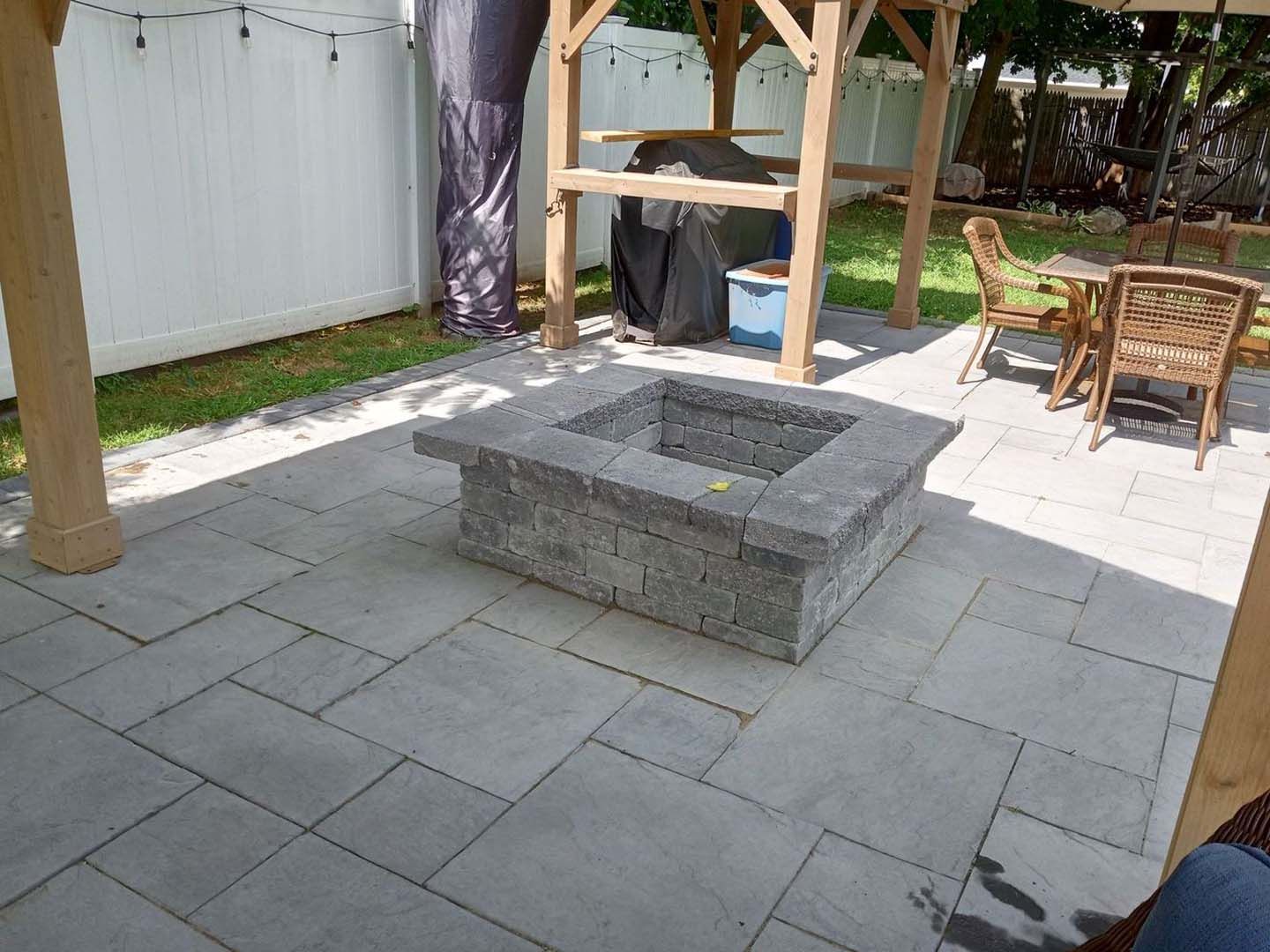A fire pit is sitting on a patio next to a table and chairs.