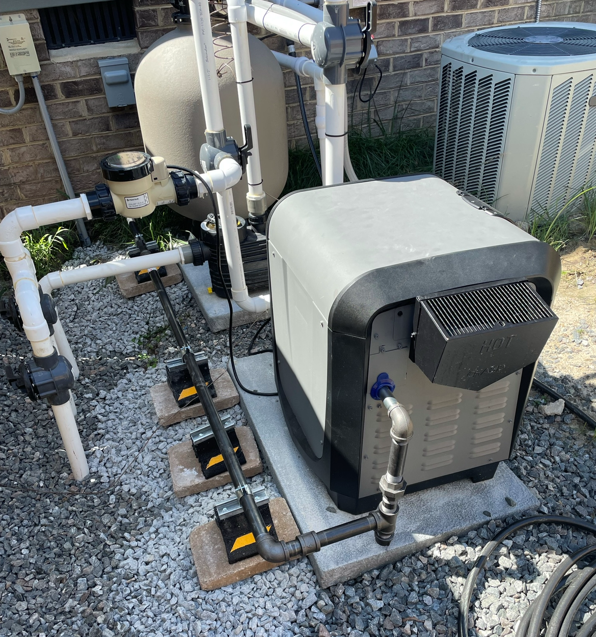 Pool equipment: filter, heater, and pumps on a gravel bed.