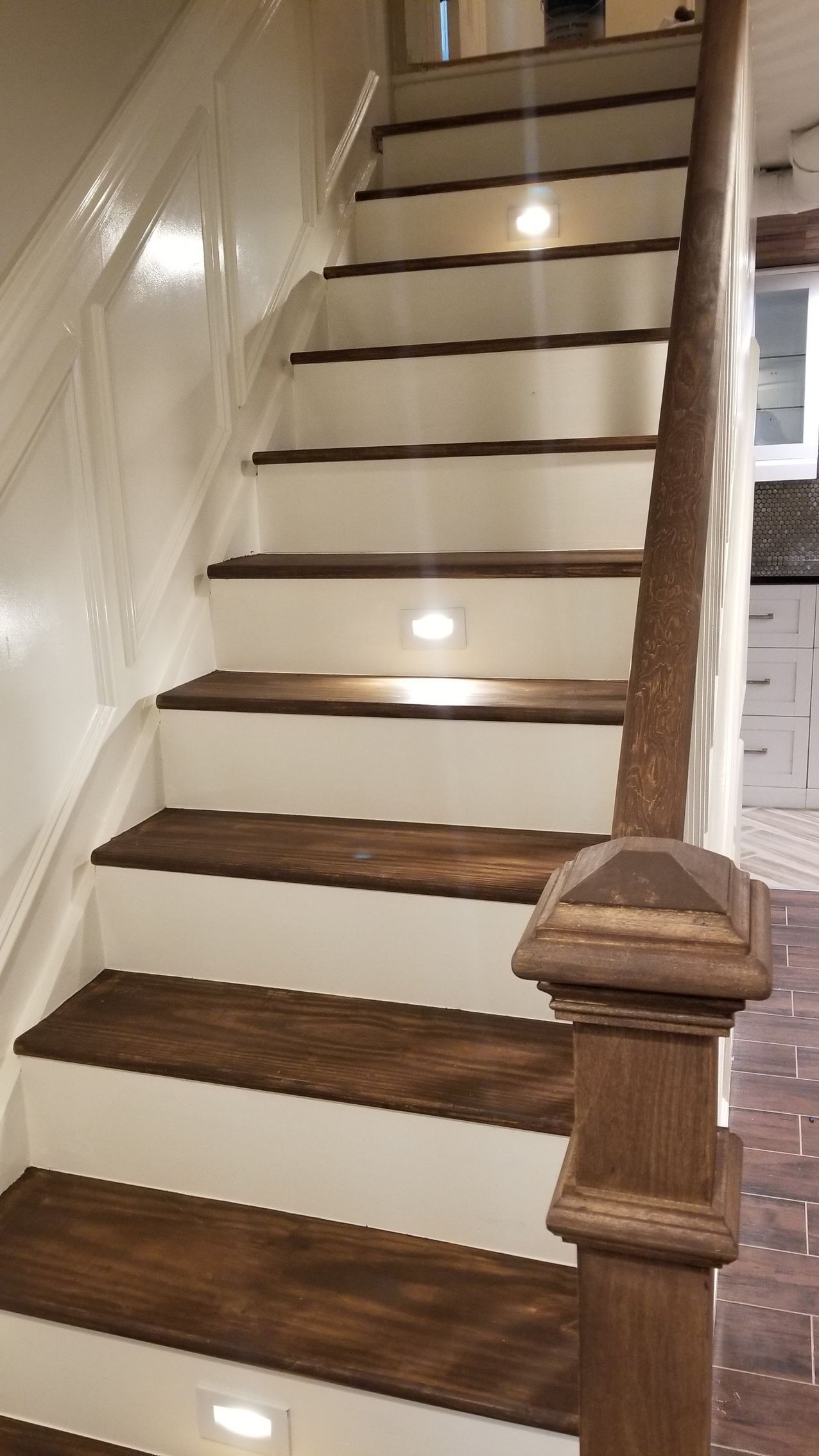 A wooden staircase with white steps and a wooden railing.