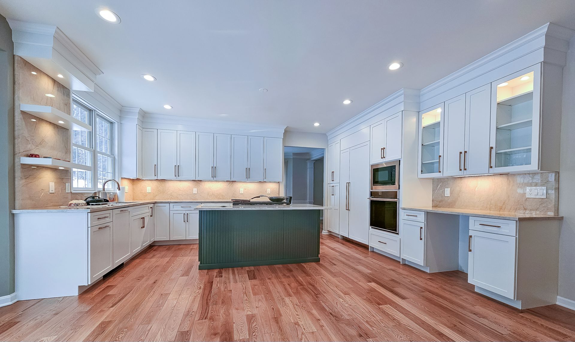 A large kitchen with white cabinets and hardwood floors.