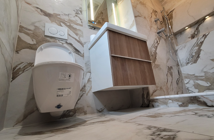 A bathroom with a toilet , sink and mirror.
