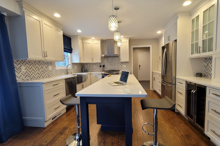 A kitchen with white cabinets and stainless steel appliances and a large island.