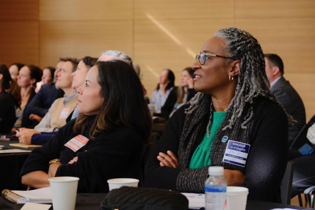 A group of people are sitting at a table watching a presentation.